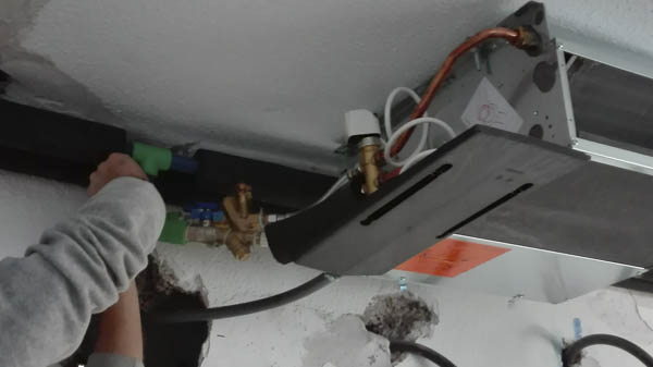Proceso de instalación de aire acondicionado mientras un trabajador manipula con las manos el cableado