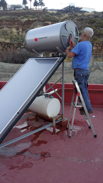 Profesional instalando un termosifón de energía solar térmica en una azotea