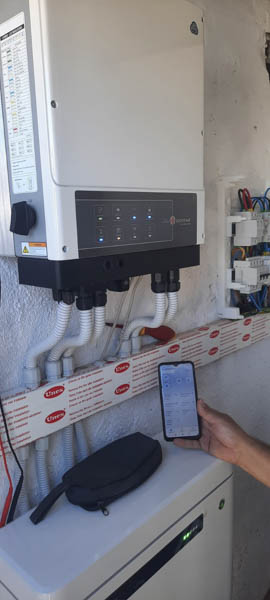 Instalación de autoconsumo de energía solar fotovoltaica vista de cerca junto a una mano sosteniendo un teléfono móvil