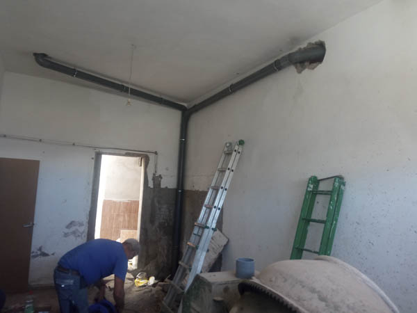 Profesional en obras en proceso de instalación de tuberías dentro de una vivienda