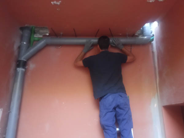 Profesional instalando tubería que atraviesa el techo por agujero